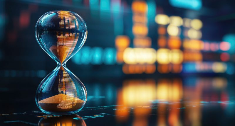 Hourglass with financial market graphics behind it