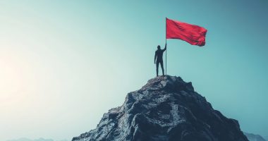 Person hoisting a red flag on a mountain