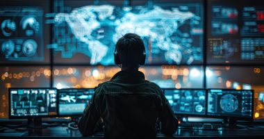 Image of a man sitting in front of a computer concentrating on defence systems