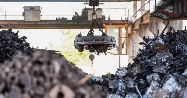 An e-waste machine hangs over piles of garbage.