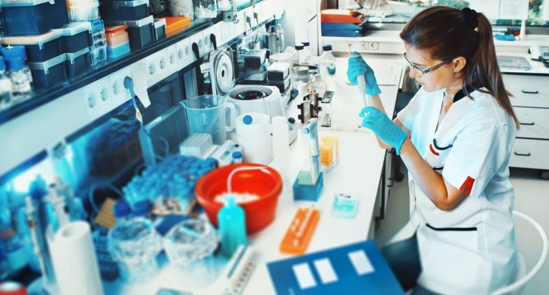 A Mayne Pharma worker in a lab surrounded by vials and bottles.